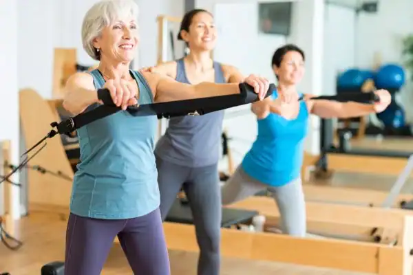 Toning Arms After 60: Empowering Womens Fitness Through Effective Weight Training 2 older woman doing weight training Northolt and resistance in the gym to tone upper arms